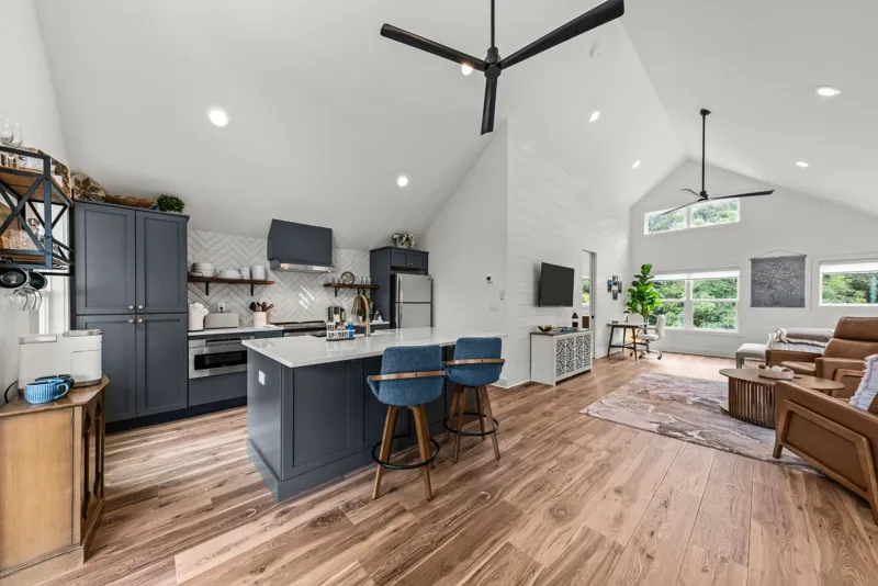 Full kitchen with navy cabinets and an island with stools, open to the living area